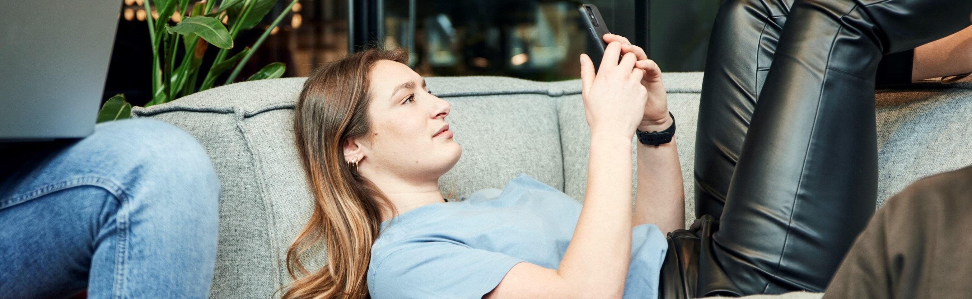 Women lies on couch with phone